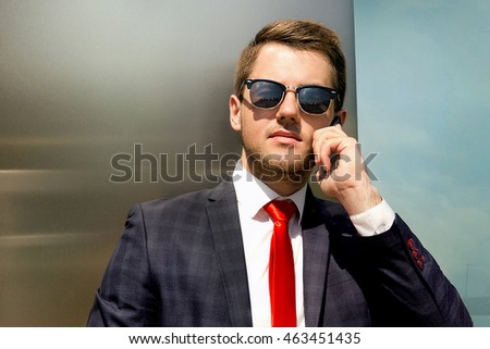 Handsome young man in fashion sunglasses calling on the phone