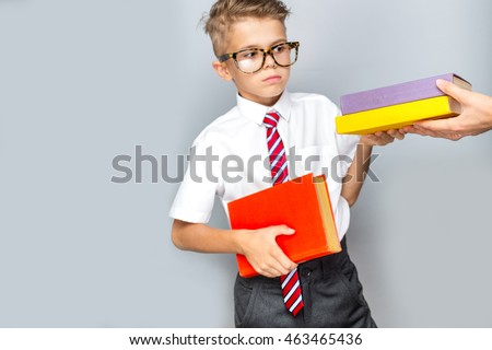 Back to school concept. Cheerful smiling little boy holding book on a grey background, focus on hands with books