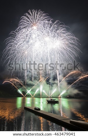 Ignis Brunensis green silver gold colored firework resembling aster flower reflecting on dam water surface. Long exposure night graphical photography using creative tilt effect by tilt-shift lens.