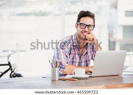 Portrait of young man sitting at his desk in the office Royalty-Free Stock Photo #463500722