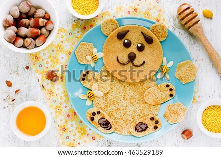 Bear-shaped pancakes with honey and nuts - creative idea for children breakfast, funny food art for kids, edible picture on plate top view