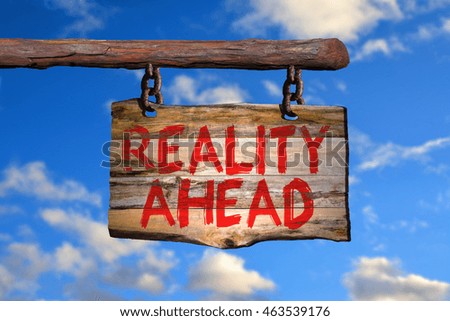 Reality ahead motivational phrase sign on old wood with blurred background