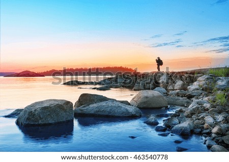 Silhouette of tourist with camera on rocks mysterious island at sunset