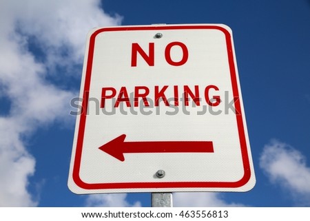 No Parking Sign with Arrow Pointing Left against Blue Sky with Clouds