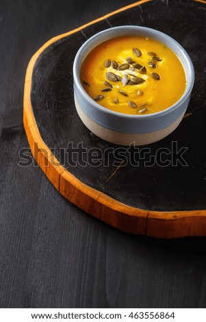 Fresh homemade carrot soup with pumpkin seeds and sour cream in a blue vintage plate. 