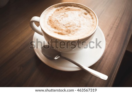 Cappuccino. Cup of coffee with milk foam stands on wooden table, vintage tonal correction photo filter, old style effect