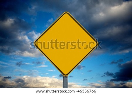 Blank warning traffic sign against cloudy sky