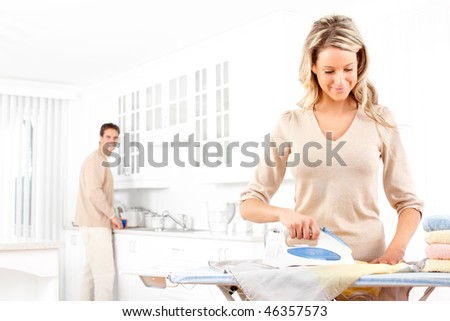 Happy young beautiful woman ironing clothes