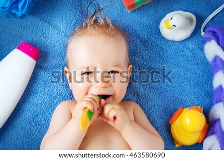 one year old baby lying on towel with washing tools