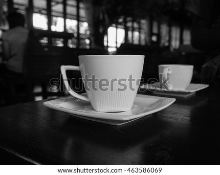 White cup of coffee on the wooden table in cafe restaurant . Black and White picture