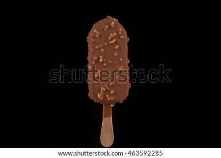 Vanilla ice cream covered with chocolate and peanuts on black background