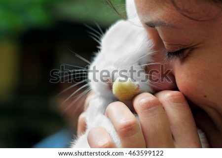 Girl close eyes and kiss little white rabbit.Hug rabbit.Selective focus. Focus on eye of girl.