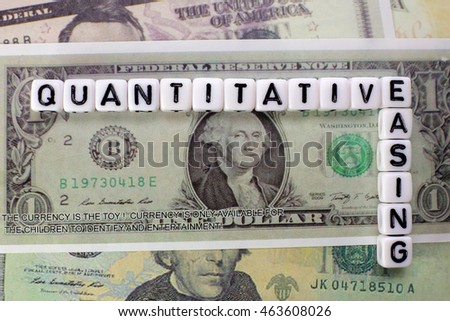 Quantitative Easing written on white cube with dollars background for QE concept. Royalty-Free Stock Photo #463608026