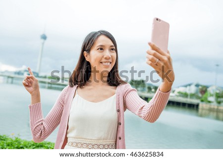 Woman taking selfie by cellphone in Macau city