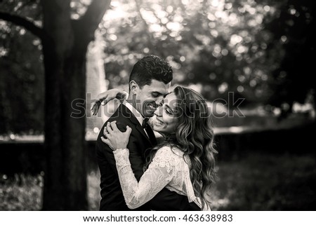 Black and white picture of smiling groom holding laughing bride in his arms