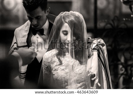 Jewish wedding. Black and white picture of groom covering with his shawl bride's shoulders