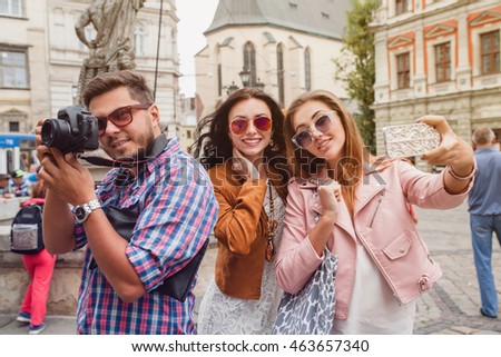 young hipster company of friends traveling, vintage style, europe vacation, sunglasses, old city center, happy positive mood, smiling, embracing, taking pictures, making selfie photo on smartphone