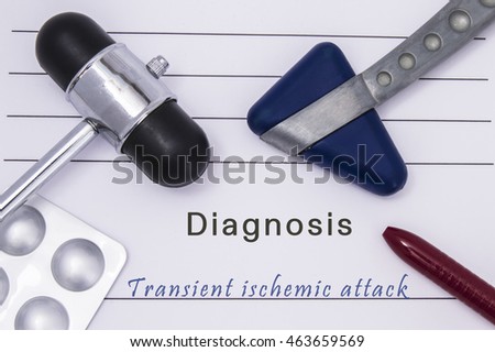 Printed medical form with text diagnosis Transient ischemic attack, two medical neurological reflex hammers, medicine pills in a blister pack and a ballpoint pen on the table in the doctor's office