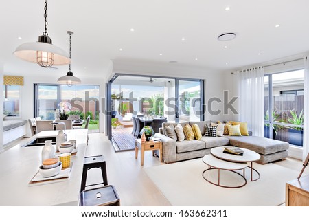 Modern kitchen area attached to the living room beside a patio and dinner area near to outside entrance, there are hanging lamps Royalty-Free Stock Photo #463662341