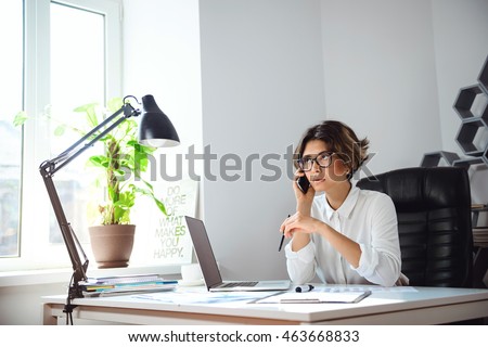 Young beautiful businesswoman speaking on phone at workplace in office.