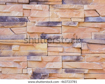 a wall from an artificial beige and gray stone facade with rough fractured surfaces
