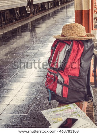 Backpack, hat, cellphone and map on bench at the station. Vintage tone