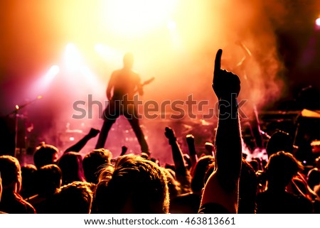 silhouette of guitar player in action on stage in front of concert crowd Royalty-Free Stock Photo #463813661