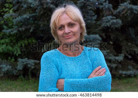Smiling happy ellderly woman stands with crossed arms