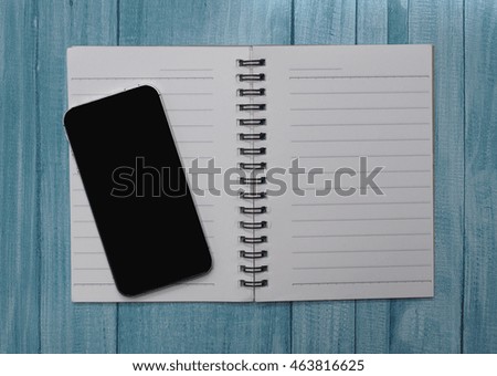 Working desk with smart phone and paper note on blue wood background 