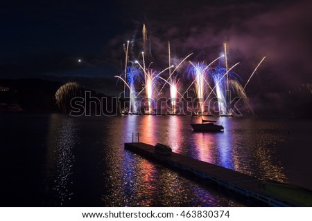 Ignis Brunensis silver gold red blue colored firework resembling aster flower reflecting on dam water surface. Long exposure night graphical photography using creative tilt effect by tilt-shift lens.