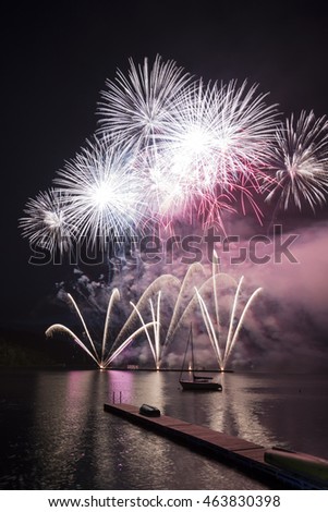 Ignis Brunensis silver gold red colored firework resembling aster flower reflecting on dam water surface. Long exposure night graphical photography using creative tilt effect by tilt-shift lens.