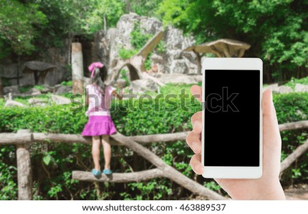 woman use mobile phone and blurred image of a child in the zoo

