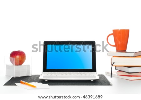 office work desk with laptop computer, pile of books, cup of coffee and apple