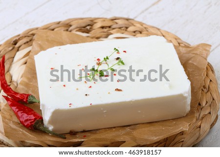 Feta brick cheese on the board wth thyme and pepper