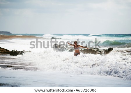 Young cute happy female in bikini in huge waves