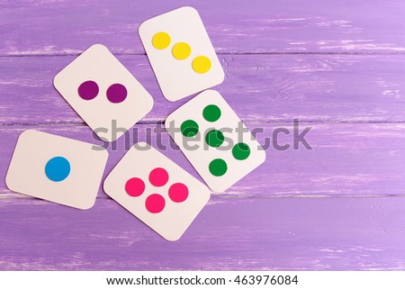 Kids colored flash cards on lilac wooden background with copy space for text. Handmade cardboard cards to teach children color, shape and quantity. Early development in kindergarten, at home 