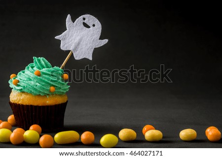 Halloween cupcake with ghost and candies on black background

