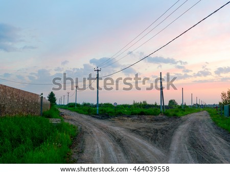 Fork of two roads in the village early in the morning at twilight.