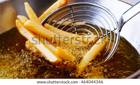 Cooking french fries. Close up of Frying french fries in the fryer in hot oil Royalty-Free Stock Photo #464044346
