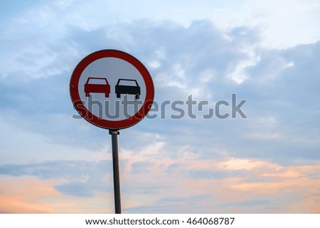 Traffic sign on a blue sky with two cars on it