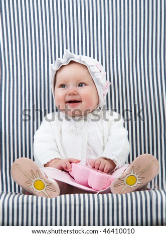 Lovely picture of playing baby girl. She sitting on the armchair