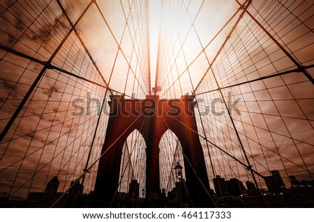 Brooklyn bridge silhouette with a dramatic red sky and sun rays. New York City. USA.