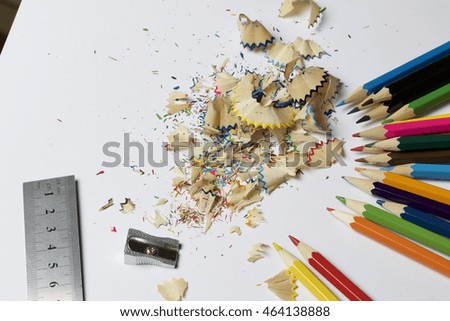Colour pencils. Shavings from pencils. Iron ruler and pencil sharpener lie nearby. Located on a white background.