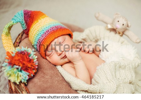 newborn baby in colorful hat asleep in his room