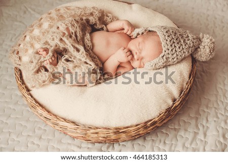 amazing newborn baby sleeps under a brown scarf
