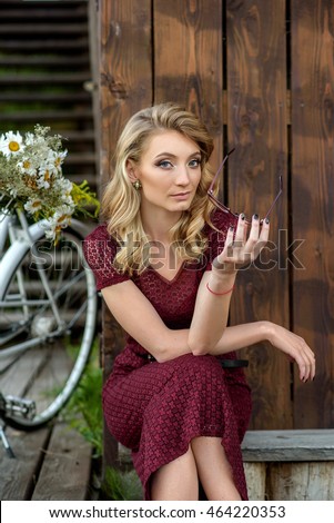 Beautiful girl sitting next to vintage bike with flowers in the basket.Photo stylized film