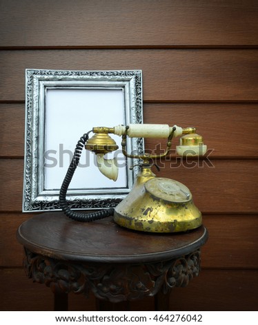 Phone antique brass frames and metal Sliver engraving. Placed on a wooden table carved with floral motifs dimensional height rear wall of brown wood.