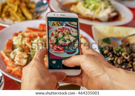 food photographer taking a food picture using his smartphone,in a chinese restaurant
