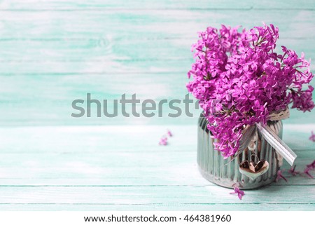 Background with fresh violet lilac flowers in vase  on turquoise painted wooden background. Selective focus. Place for text.