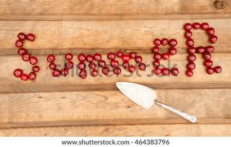 Heart made of dark cherries. Red fruit on wooden background. Summer